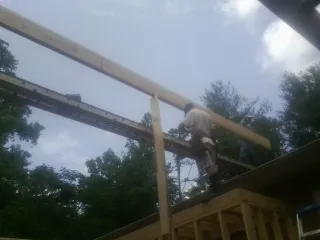 Carpenter setting a ridge beam over a new addition frame — Ice Dam Removal by Roofing Brothers in Green Cove Springs