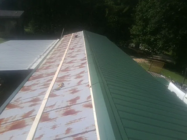 Old rusted panels beside newly installed green metal roofing — Wind Damage Roof Repair by Roofing Brothers in Green Cove Springs