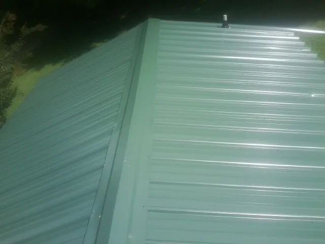 New green metal panels meeting at the ridge of a roof — Flat Roof Repair work by our crew in Green Cove Springs