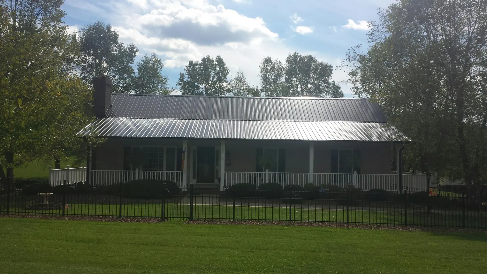 Gray metal roof on a brick ranch with a full width front porch — Gutter Guard Installation work by our crew in Green Cove Springs