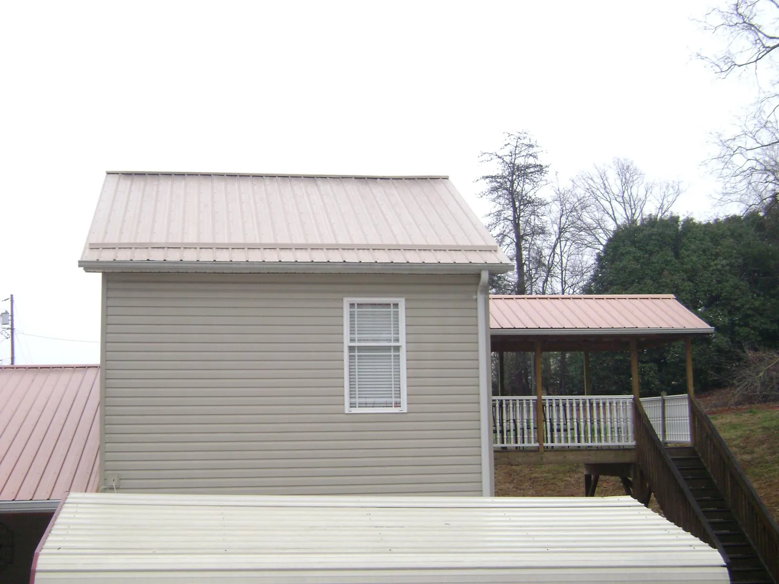 Tan metal roofs on a two story addition and attached porch, from a Roof Replacement job in Green Cove Springs