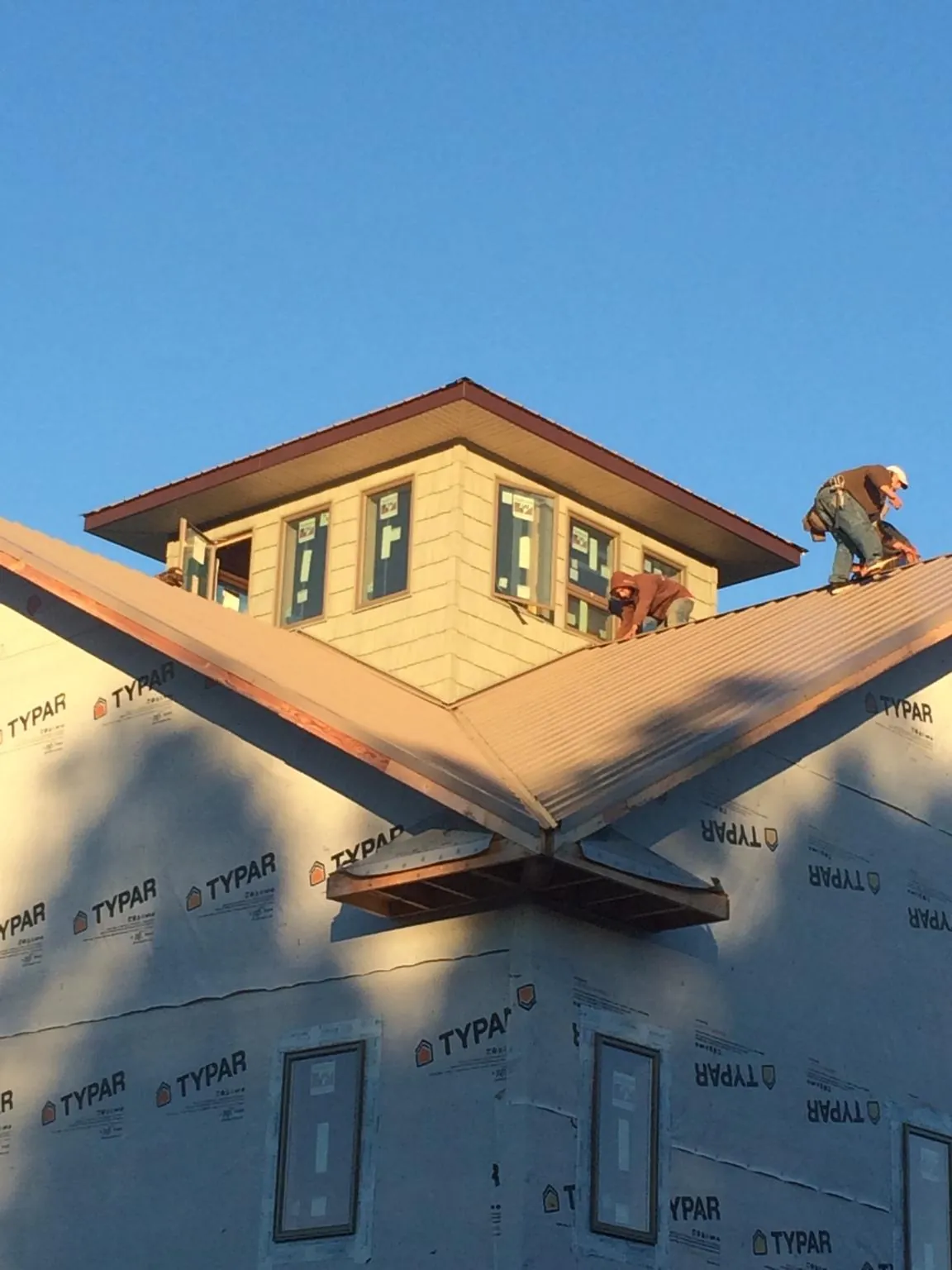 Roofers working around a rooftop cupola on a new metal roof at sunset — Roof Waterproofing in Green Cove Springs by Roofing Brothers
